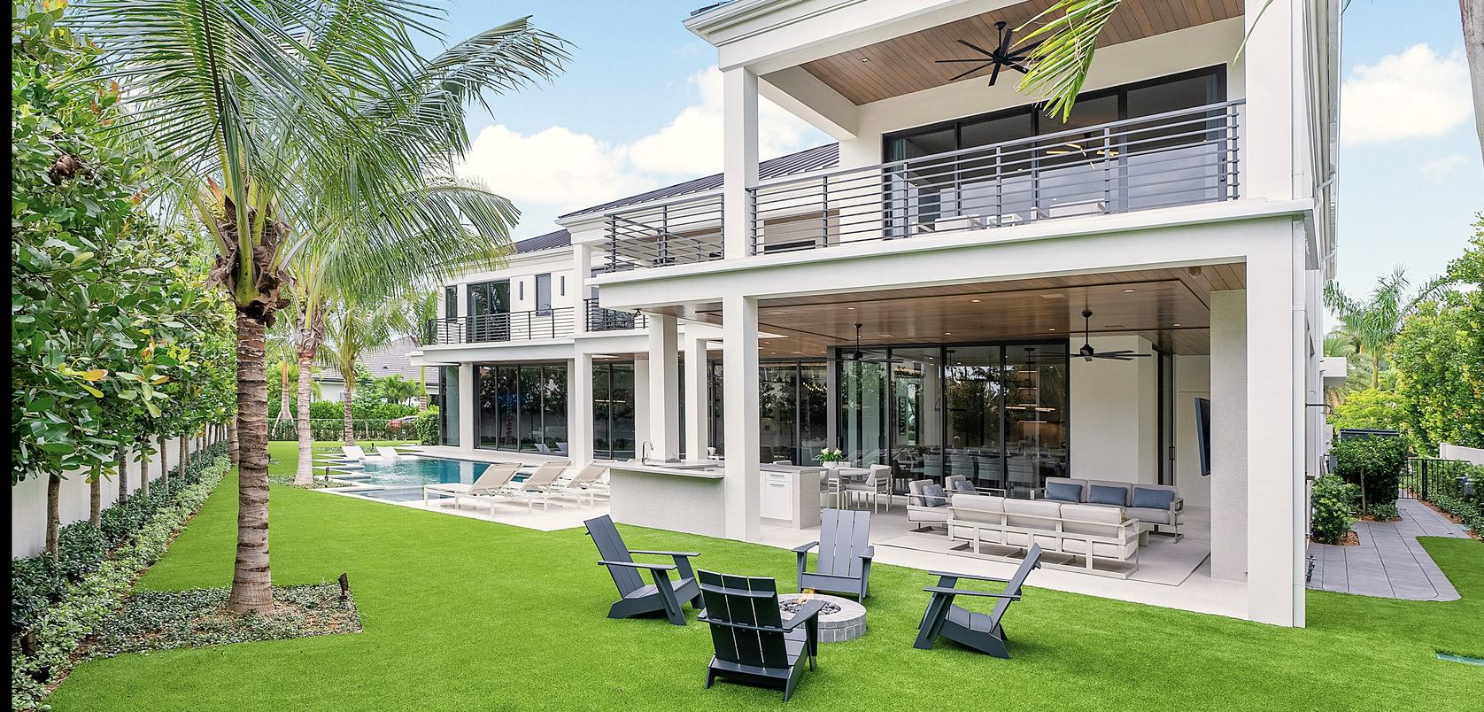 Modern home with a turf lawn, palms and patio seating