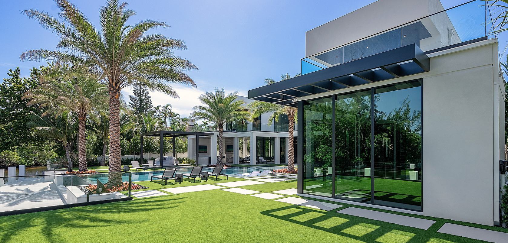 Modern home with palms, a pool and a turf lawn
